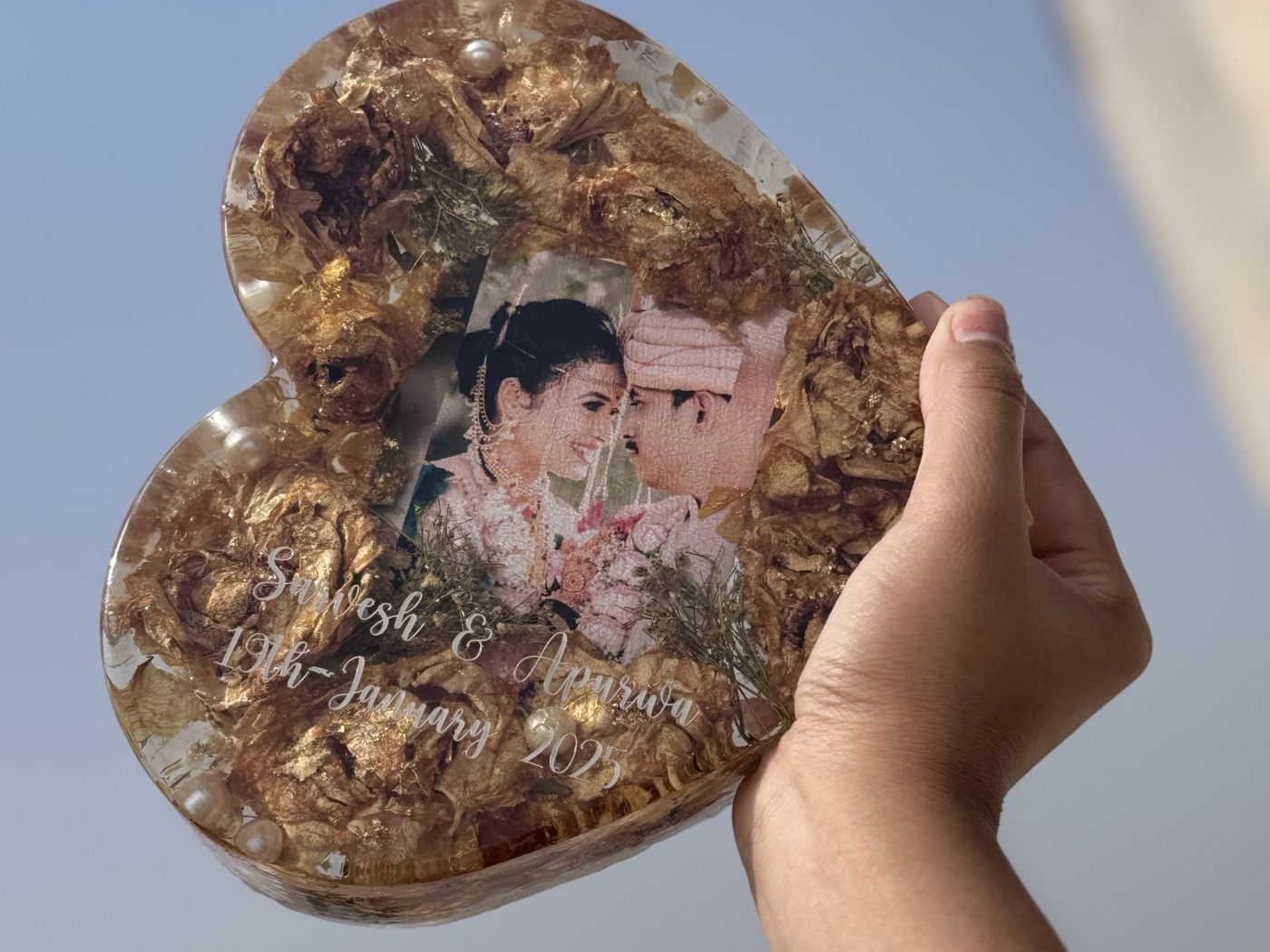 Preserved wedding flowers in a heart keepsake against the sky
